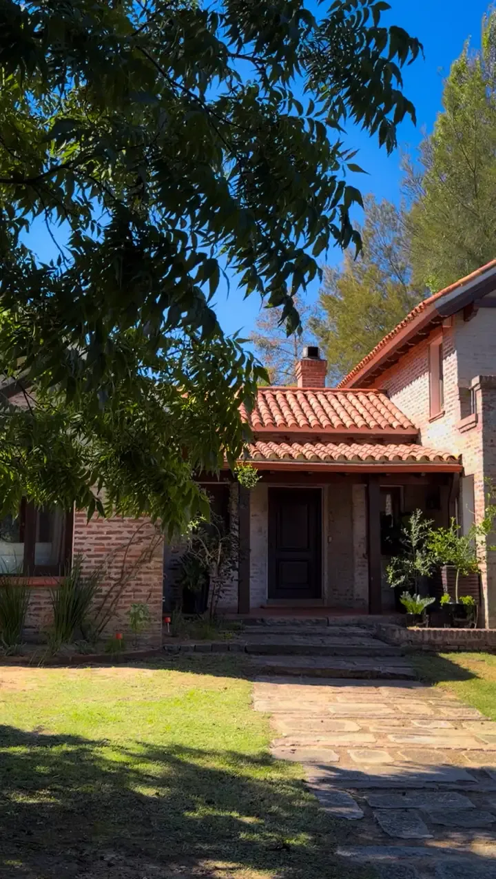 Entrada de casa con camino de piedra y árboles
